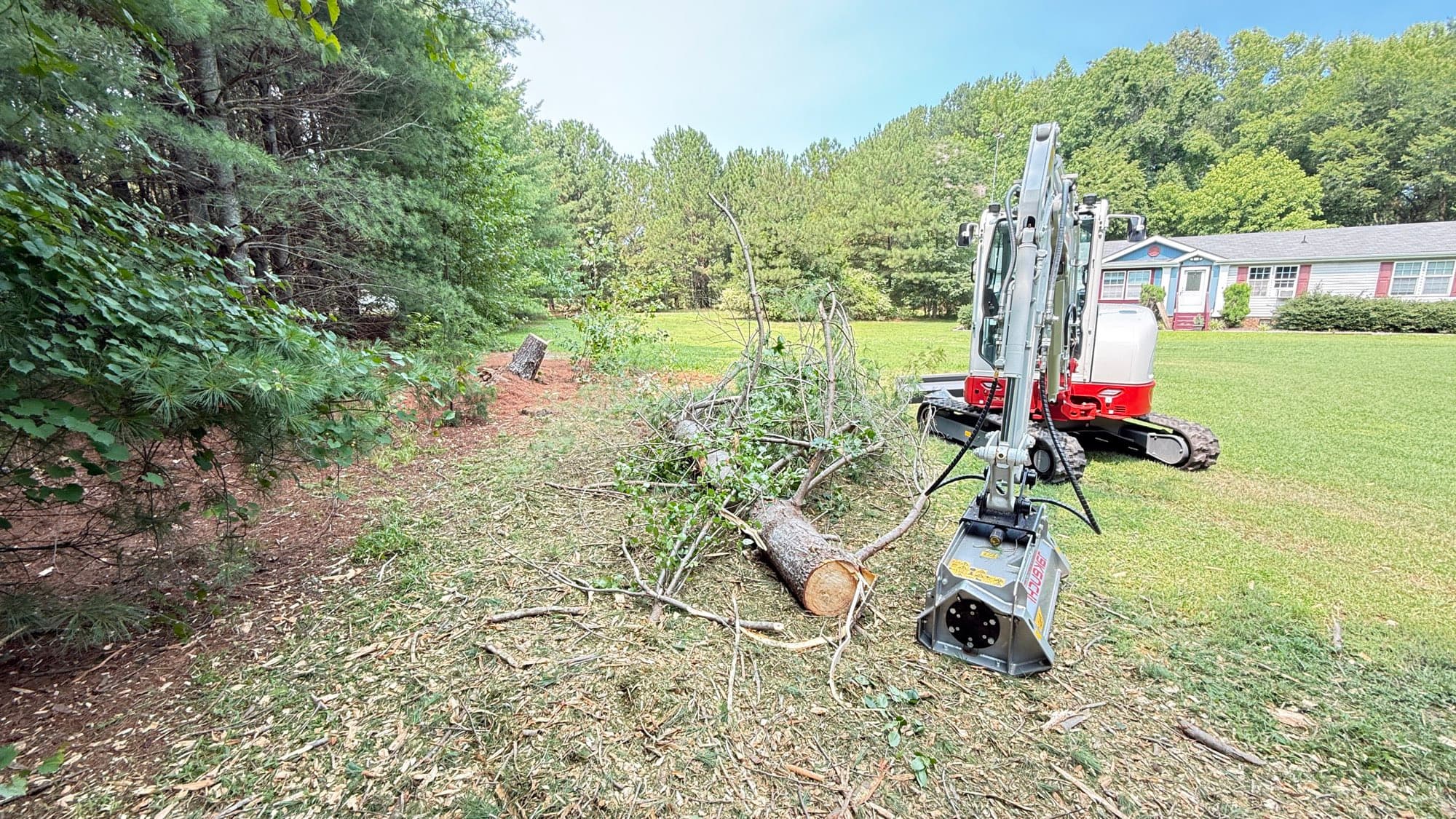 Everstone's Takeuchi excavator with a forestry mulcher head clearing brush and felled trees from a residential lot in Youngsville, NC