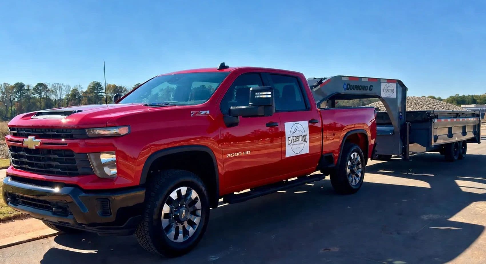 Everstone Material Hauling's red Chevrolet 2500HD towing a gooseneck trailer loaded with crushed stone